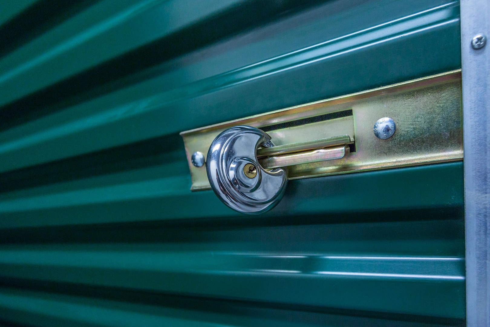 A close up of the lock on a green metal door.